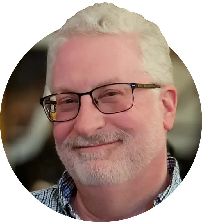 Portrait of Andrew Bronson, smiling, standing against a clean background.