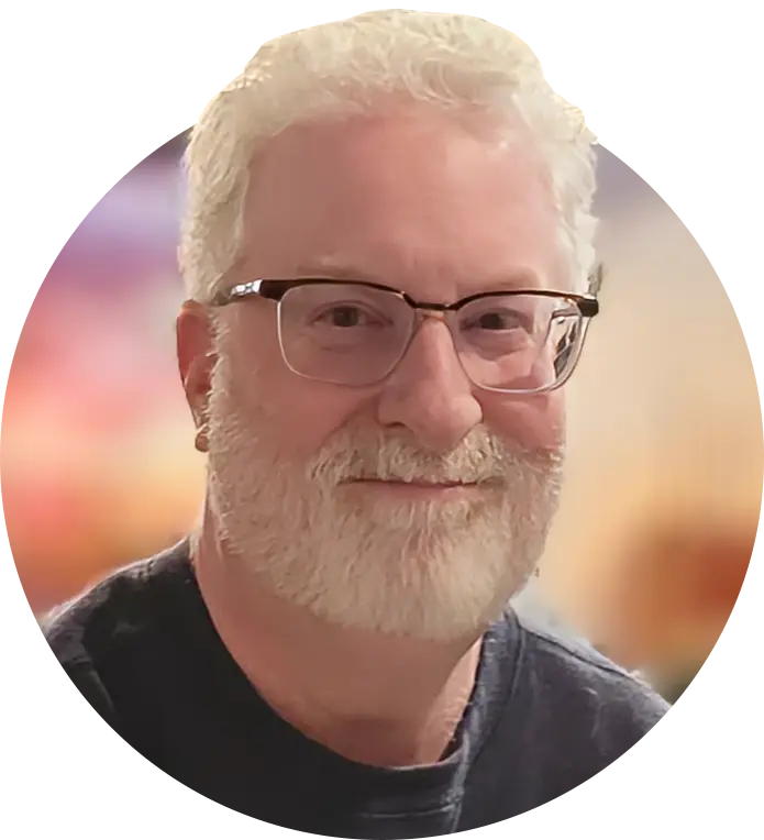 Portrait of Andrew Bronson, slightly smiling, standing against a clean background.